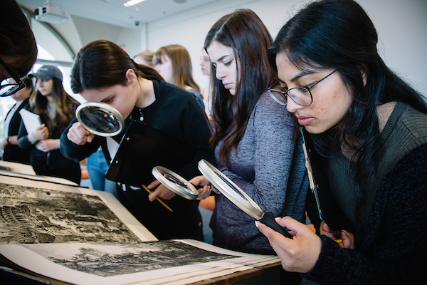 Students looking at manuscripts with magnifying glasses 