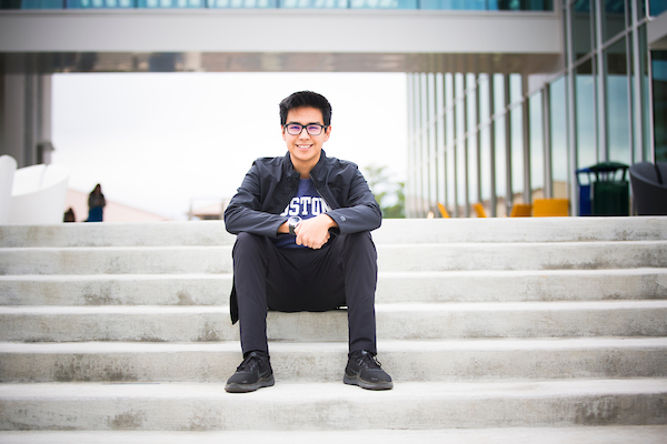 Student sitting on campus steps smiling